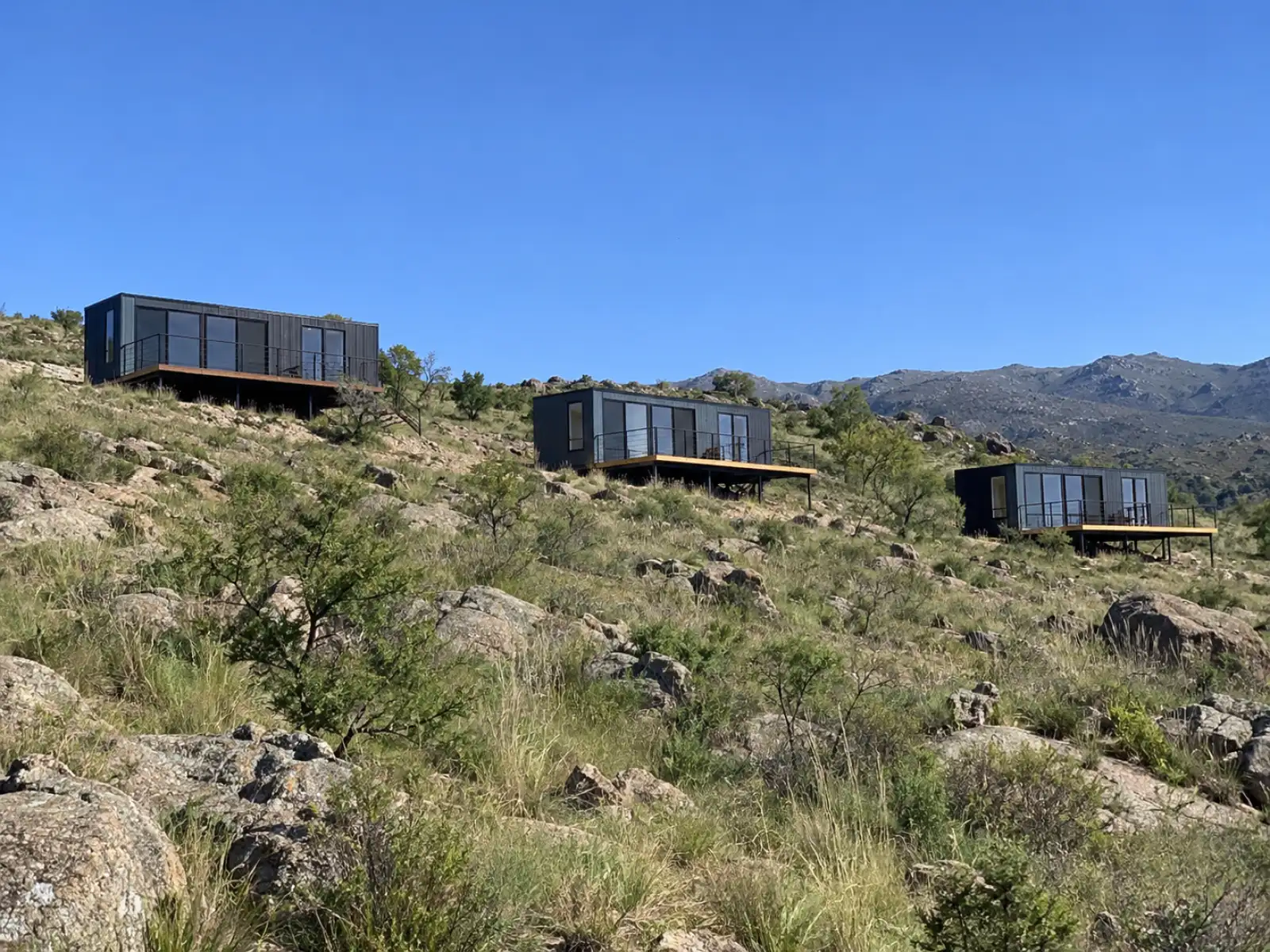 Tres cabañas de contenedor con deck en un faldeo de Tanti