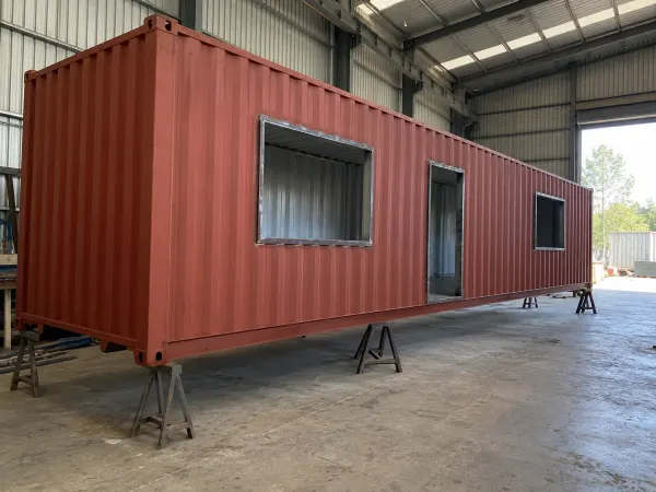 Contenedor marítimo en taller con aberturas cortadas para vivienda