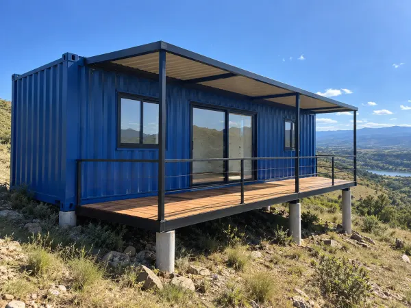 Cabaña container azul con deck sobre pilotines en Calamuchita